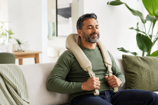 Man using a neck and shoulder massager comfortably at home